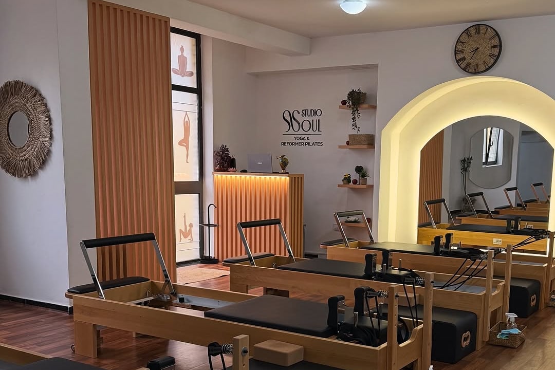 Sala Soul Studija sa drvenim reformerima poređanim uz zid i osvijetljenim lučnim prolazom u dnu prostorije
